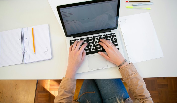 Woman Working On Laptop With Documents