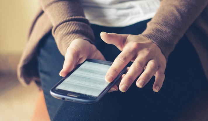 Person Holding Smartphone While Sitting